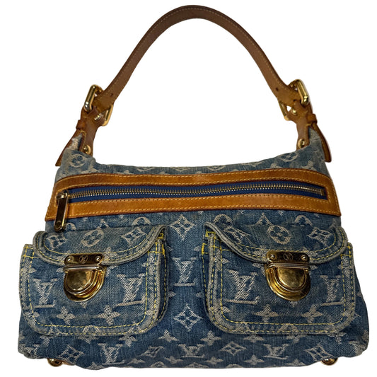 A Louis Vuitton monogram denim shoulder bag with tan leather trim and gold-tone hardware, photographed against a white fabric backdrop.